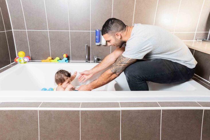 baby in bath with father using bathwater barrier